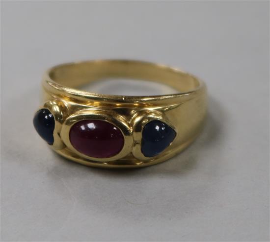 A yellow metal, cabochon ruby and sapphire three stone dress ring, size R.